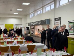 a number of royal arch masons in a canteen having a drink and breakfast bap while chatting
