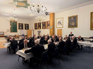 A number of masons sat at tables enjoying a meal together.